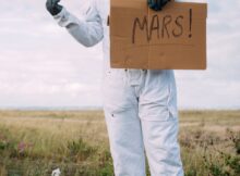 man in an astronaut costume hitchhiking
